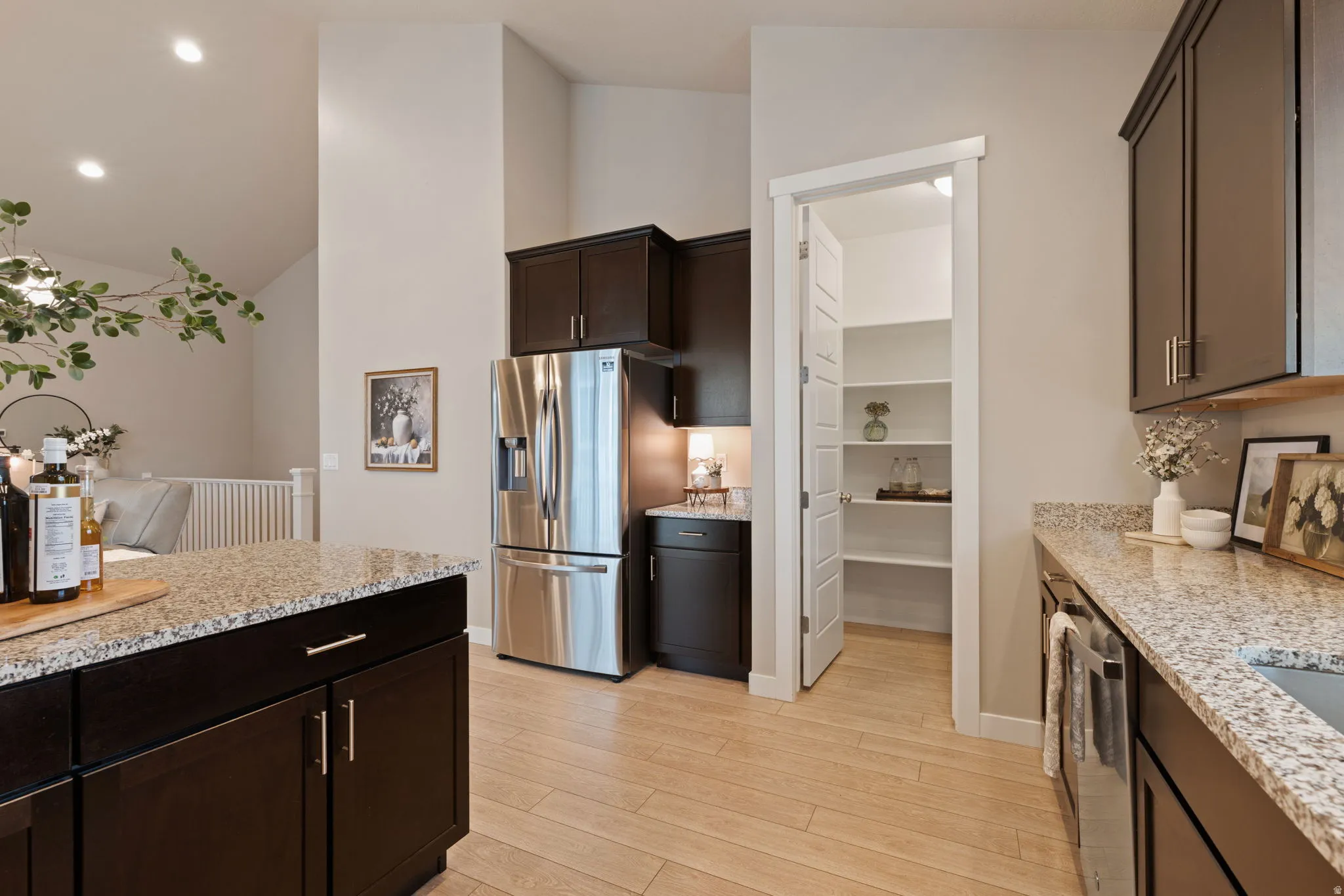 Kitchen featuring dark wood cabinetry, light granite countertops, stainless steel appliances, and wood-finish flooring