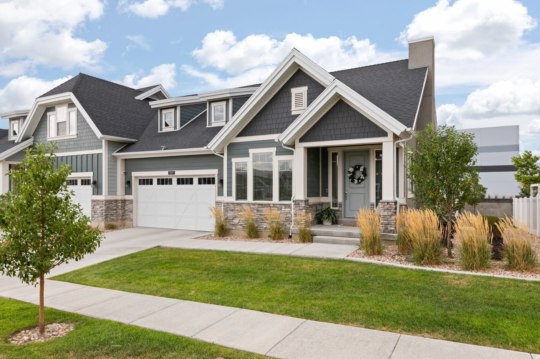 Crafted exterior featuring stone and shake siding accents, an attached two-car garage, covered porch entry, and a manicured lawn