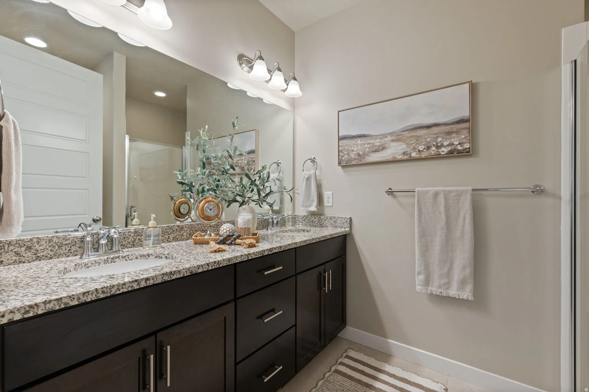 Double vanity with integrated sinks, granite countertop, dark wood-finish cabinetry, and chrome fixtures