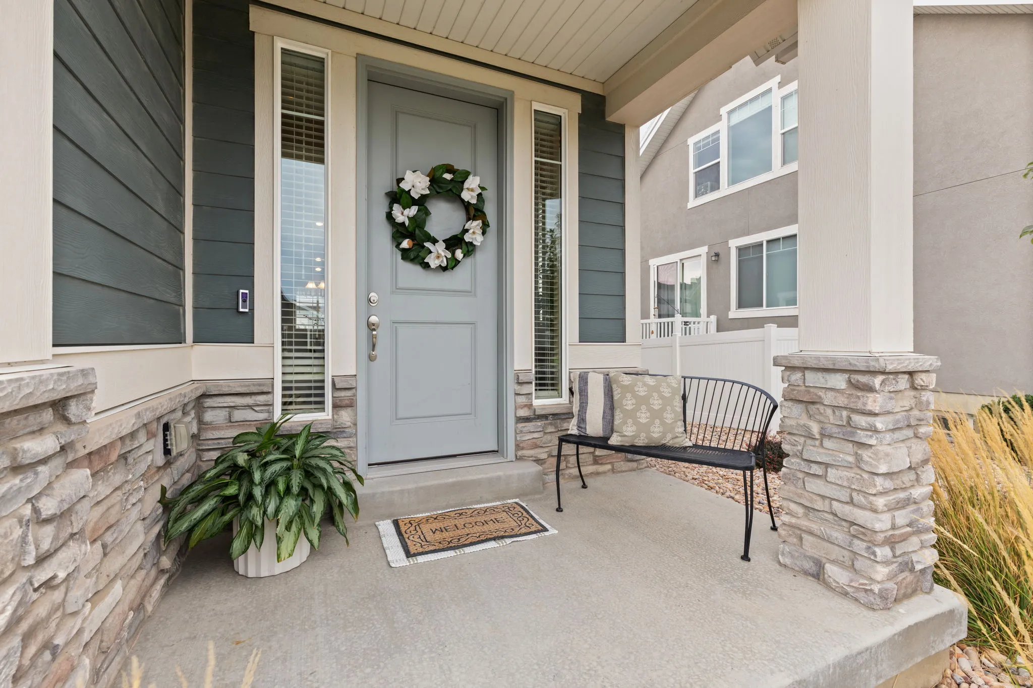 Covered porch featuring stacked stone accents, a paneled entry door, and vertical window sidelights
