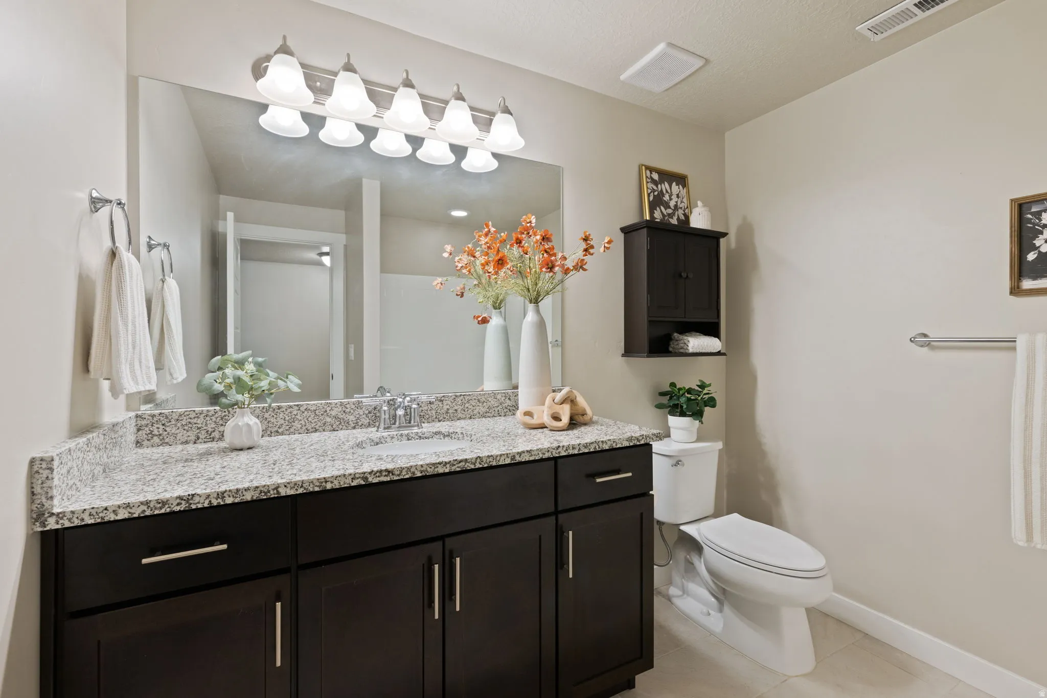 Vanity with built-in sink, granite countertop, and dark wood-finish cabinetry