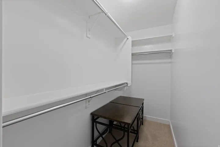 Walk-in closet with multiple white shelves and chrome hanging rods