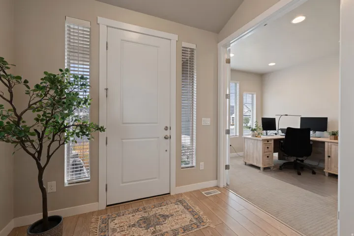 Front entry with wood-finish flooring, sidelight windows, and a panel door