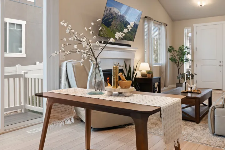 Fireplace with a white mantel, vaulted ceiling, wood-finish flooring, sliding glass door, and white paneled entry door