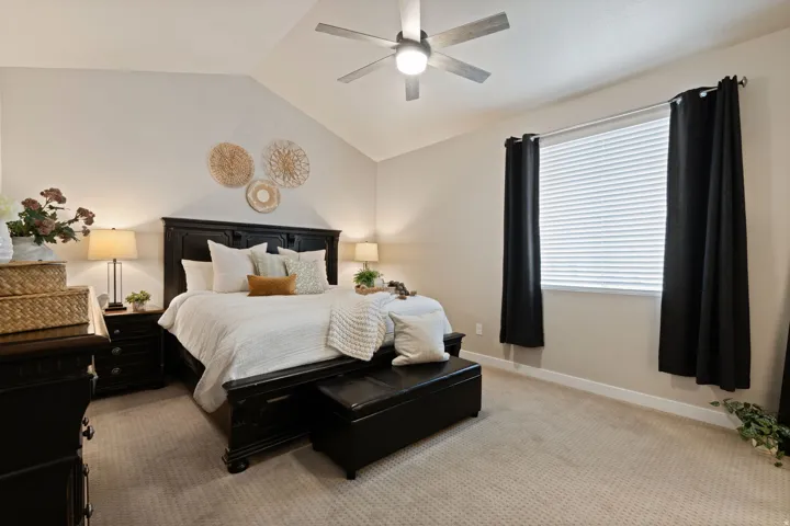Vaulted ceiling featuring a ceiling fan with integrated lighting, window with blinds and dark drapery, and neutral-toned carpeting