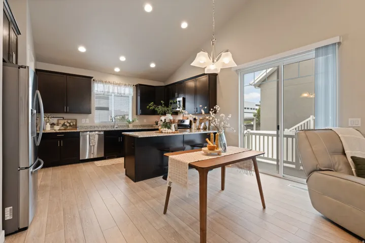 Kitchen featuring dark wood cabinetry, light-toned countertops, stainless steel appliances, and a central island