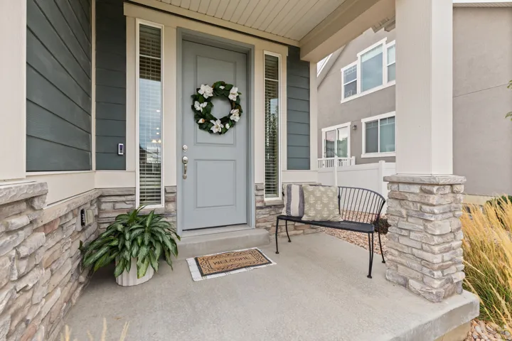 Covered porch featuring stacked stone accents, a paneled entry door, and vertical window sidelights
