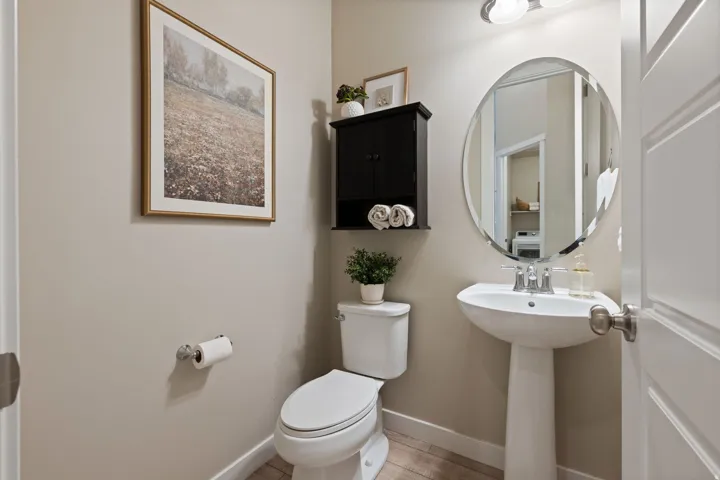 Pedestal sink with chrome faucet, oval mirror, and wall-mounted vanity light