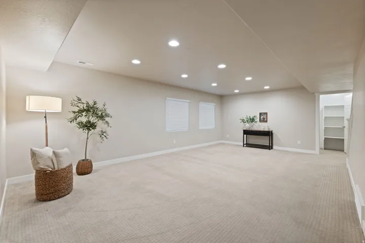 Expansive carpeted area with recessed lighting, two windows, and built-in shelving