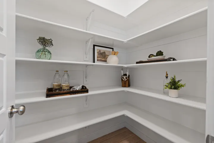 Corner pantry featuring white shelving, shiplap-style walls, and wood-finish flooring
