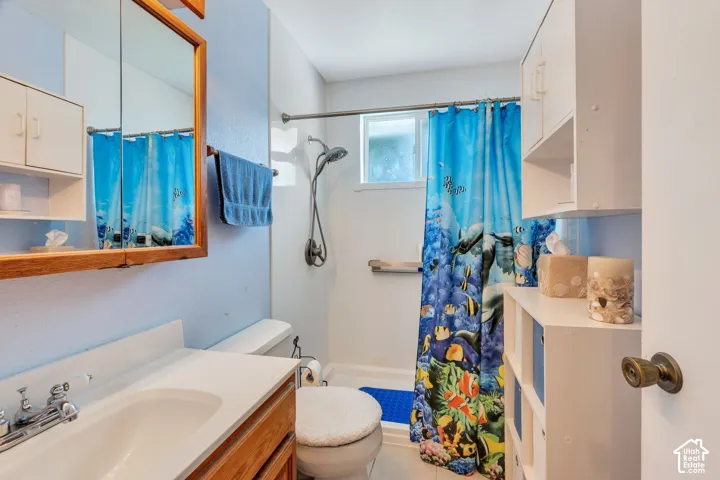 White vanity with integrated sink, wood-finish medicine cabinet, built-in shelving, and a shower with a handheld fixture