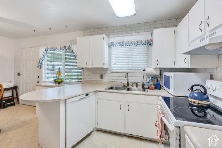 White cabinetry, white countertop, white brick-patterned backsplash, and durable vinyl flooring