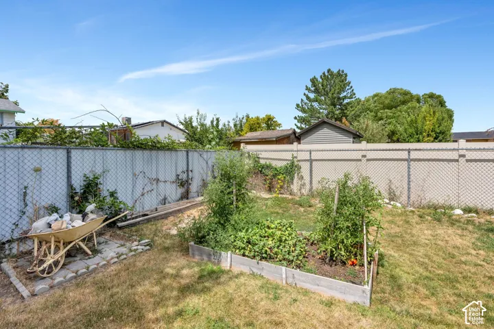 Expansive backyard featuring a raised garden bed and a combination of chain-link and privacy fencing