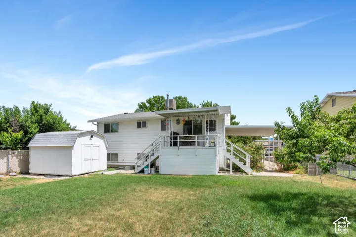 Expansive backyard featuring a manicured lawn, a detached storage shed, and a raised deck with stairs