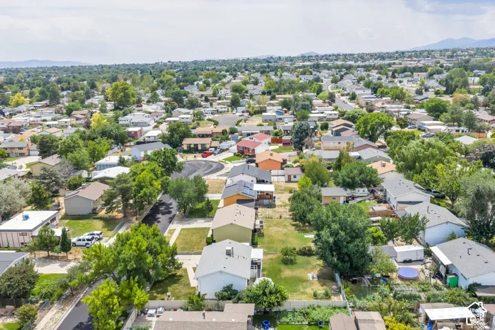 Aerial perspective of a residential neighborhood with a mix of single-story homes, mature trees, and paved streets