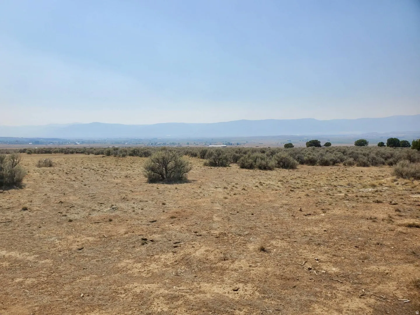 Expansive open land featuring natural desert vegetation, distant mountains, and a clear horizon