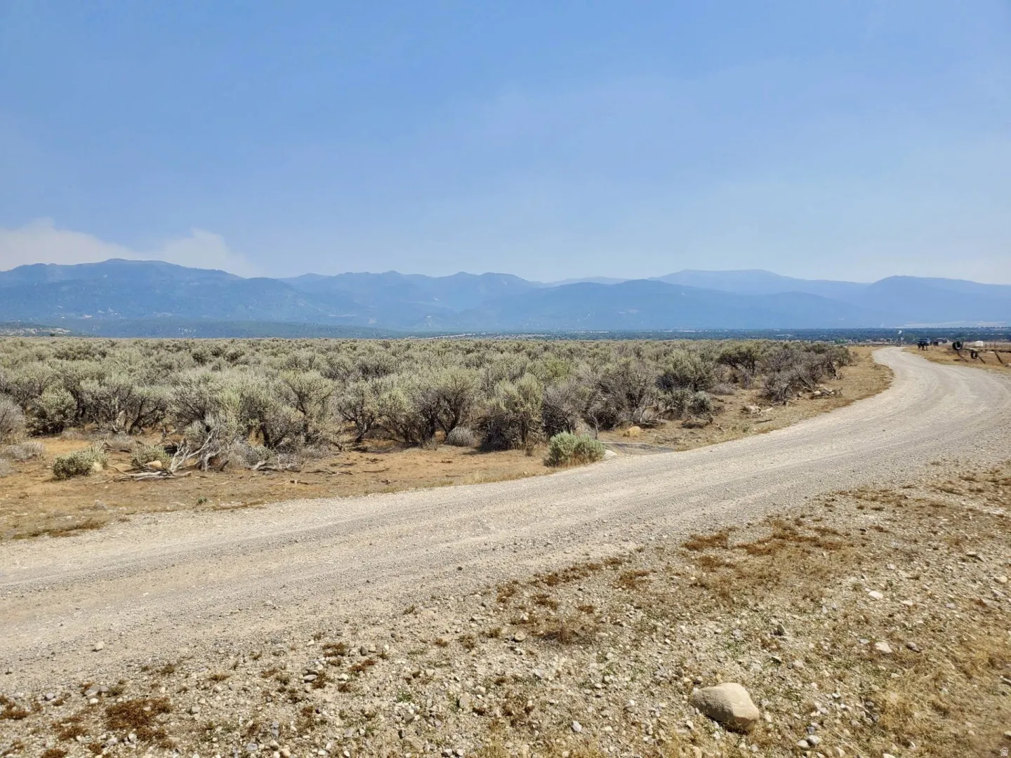 Expansive undeveloped land with a gravel road and distant mountains