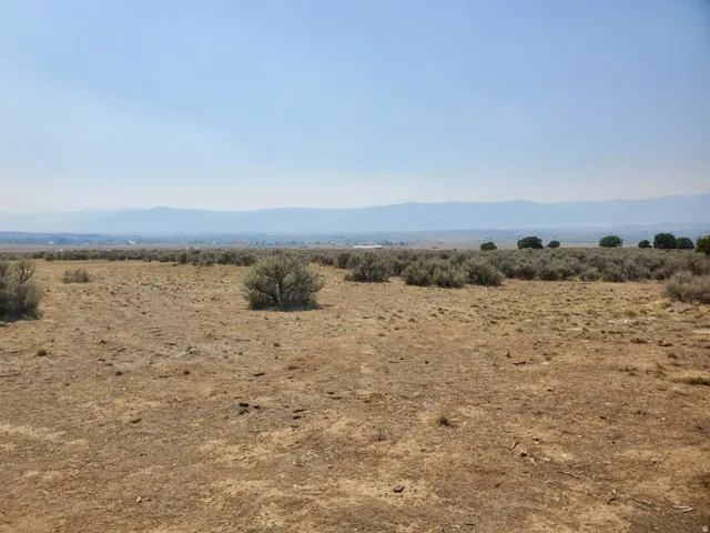 Expansive open land featuring natural desert vegetation, distant mountains, and a clear horizon