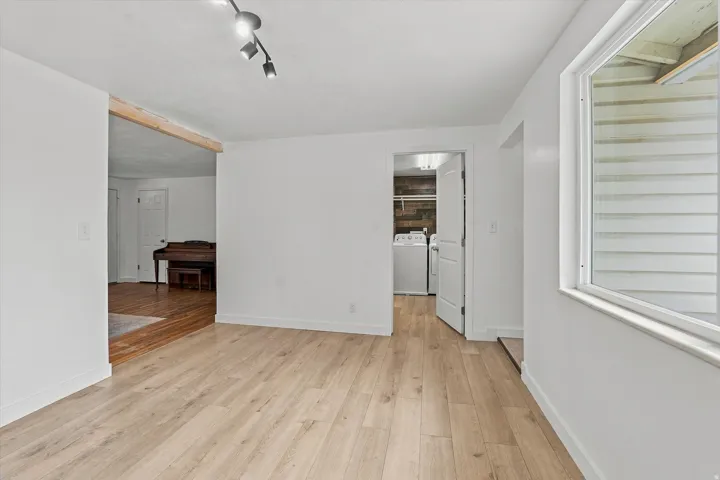 Light wood-finish flooring, white walls, track lighting fixture, and a large window