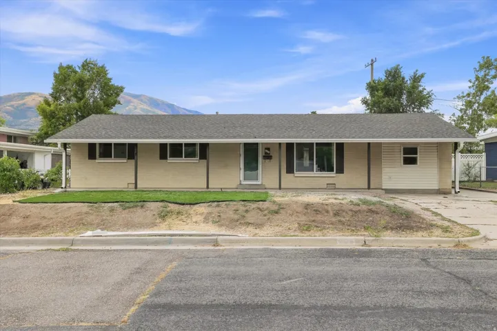 Ranch-style exterior with a neutral brick facade, a newly installed lawn area, multiple windows with dark shutters, and a covered front entry