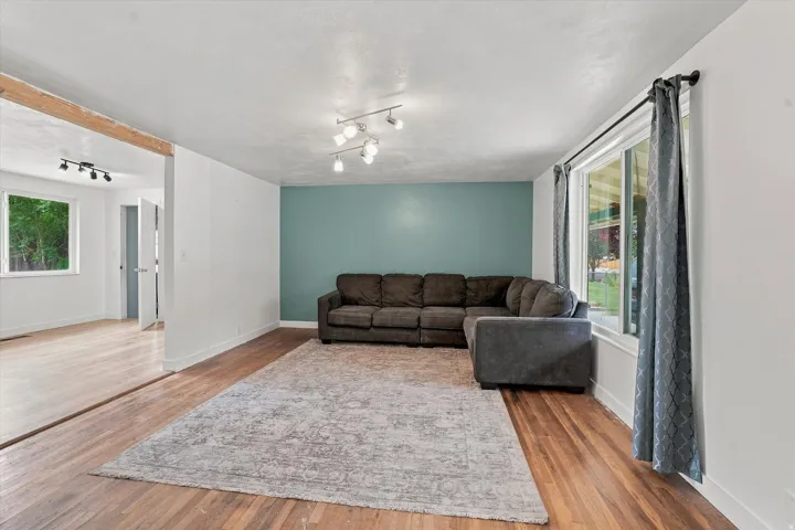 Wood-finish flooring throughout, featuring a natural exposed beam and abundant natural light from multiple windows