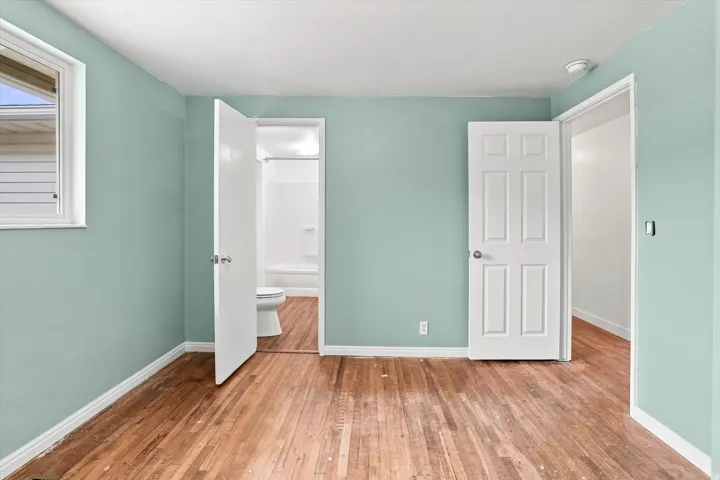 Hardwood-style flooring throughout, light blue wall paint, white trim, and a window with white casing
