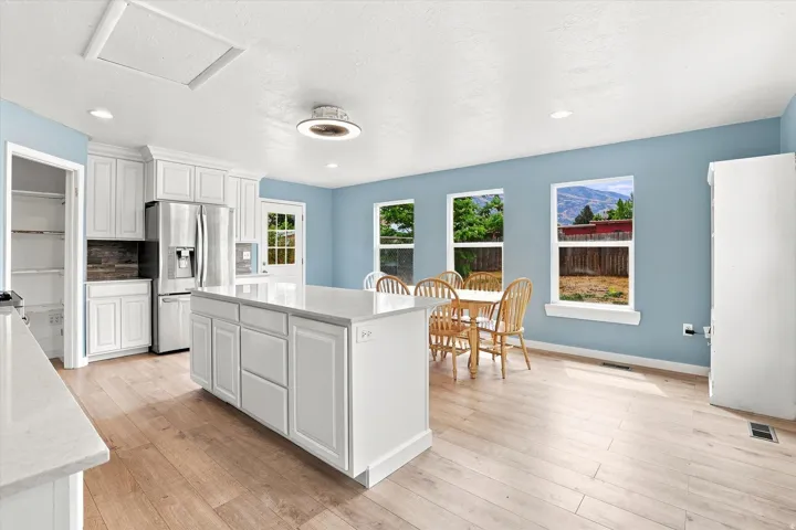 Kitchen featuring white cabinetry, a central island with a light-toned countertop, wood-finish flooring, and recessed lighting