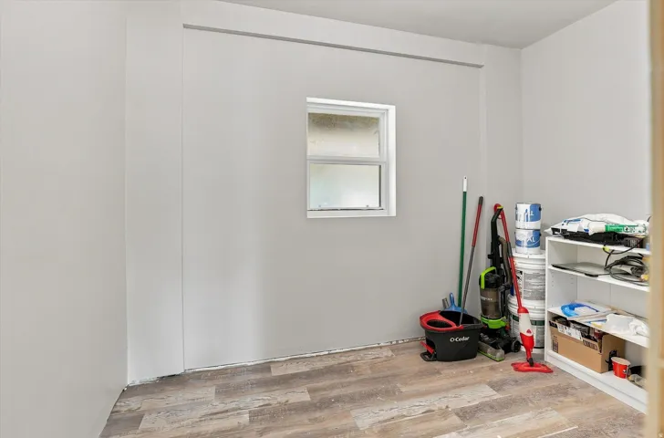 Wood-finish flooring with white walls and a window