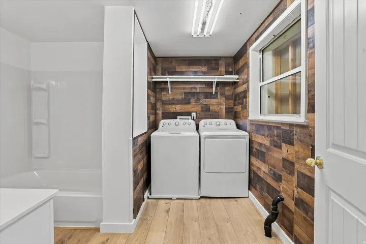 Wood-finish wall paneling, wood-finish flooring, white built-in shelving, and a white framed window
