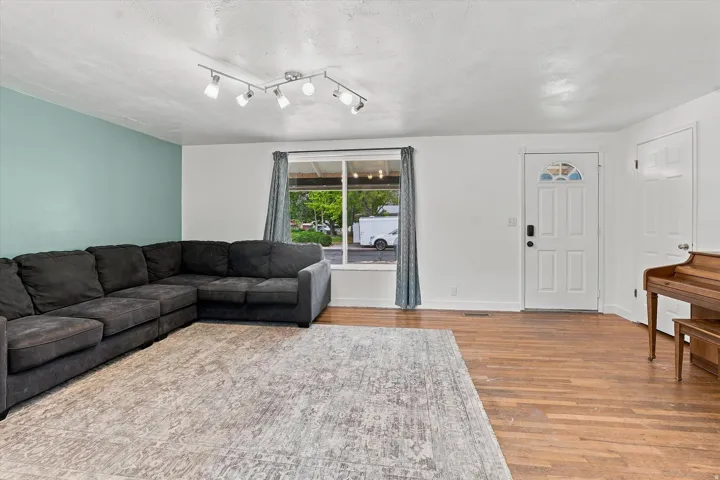 Wood-finish flooring, white paneled door with an arched glass insert, track lighting, and a large window
