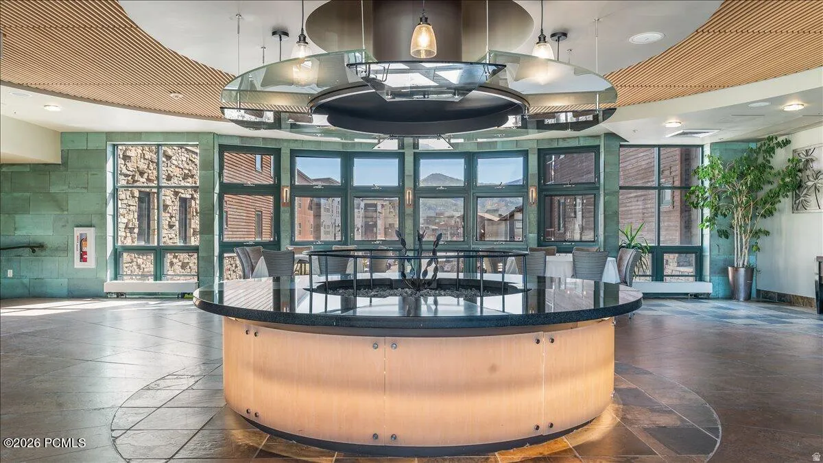 Curved architectural ceiling, stone accent walls, circular central fixture, multiple windows, and tile flooring