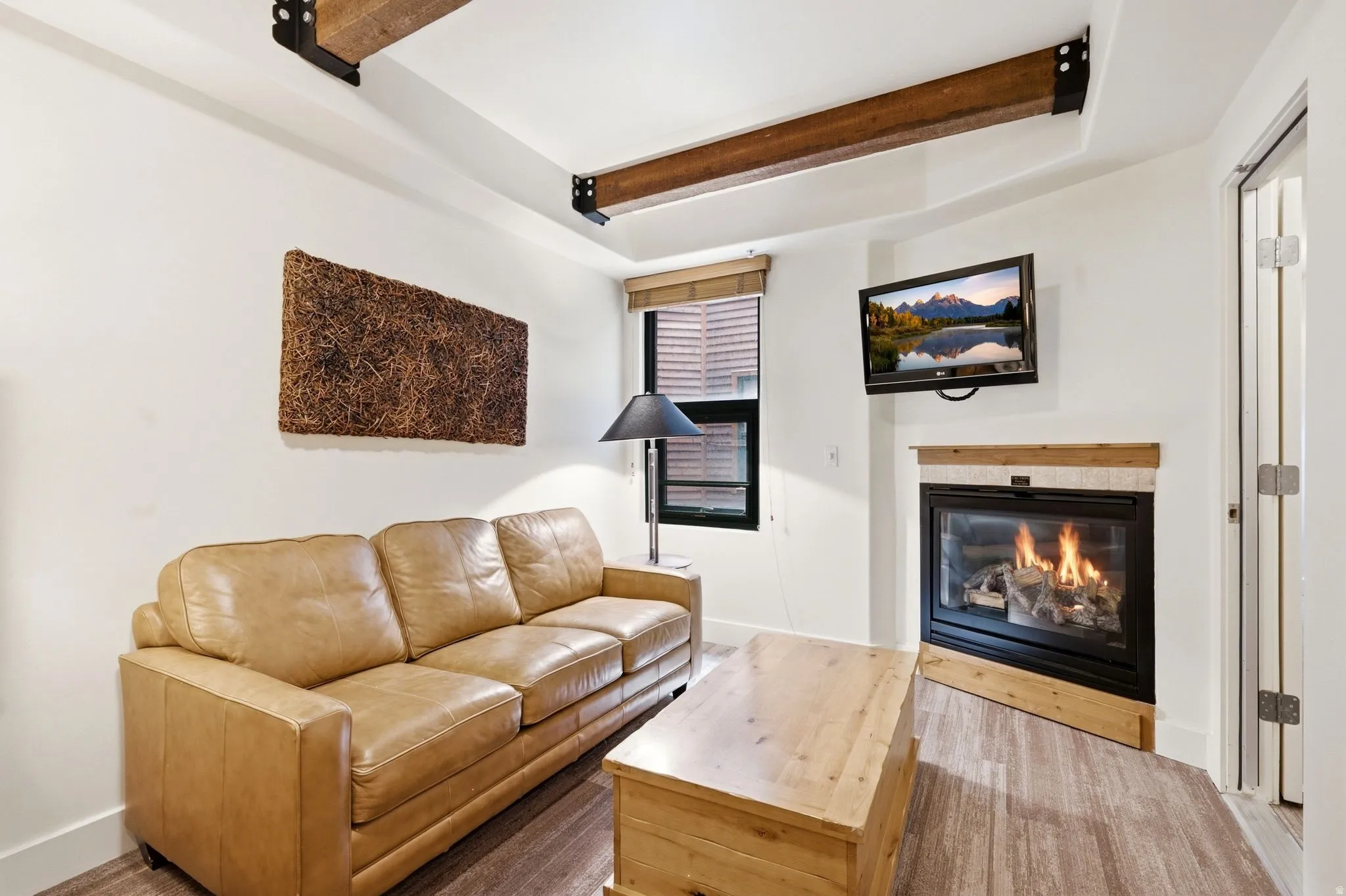 Living area featuring exposed wood beams, a built-in fireplace with a wood mantle, and wood-finish flooring