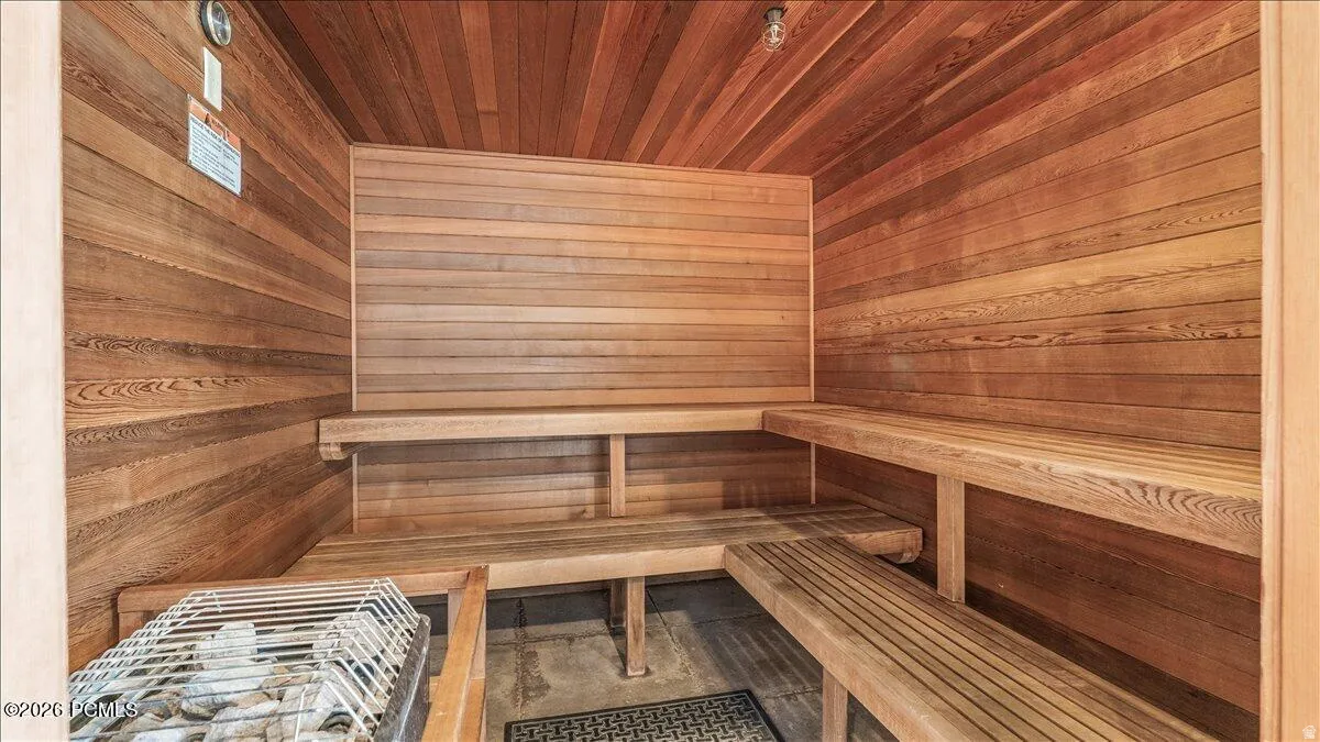 Wood-paneled sauna featuring a multi-tiered slatted bench and a stone heater