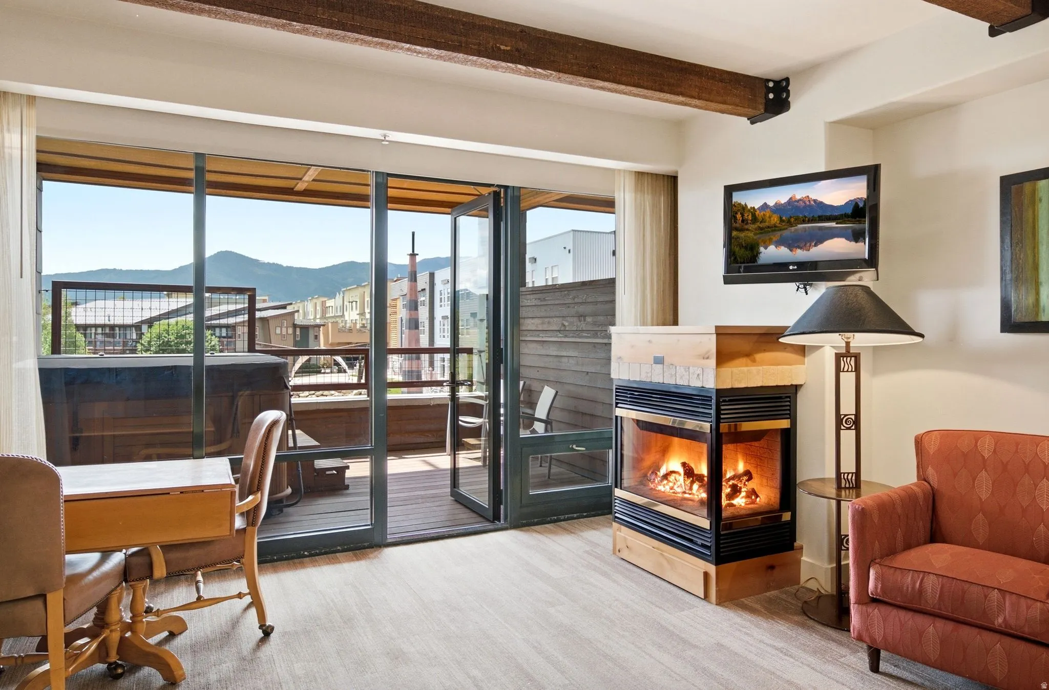 Exposed wood beams, a built-in fireplace with a stone surround, and a wall-mounted television