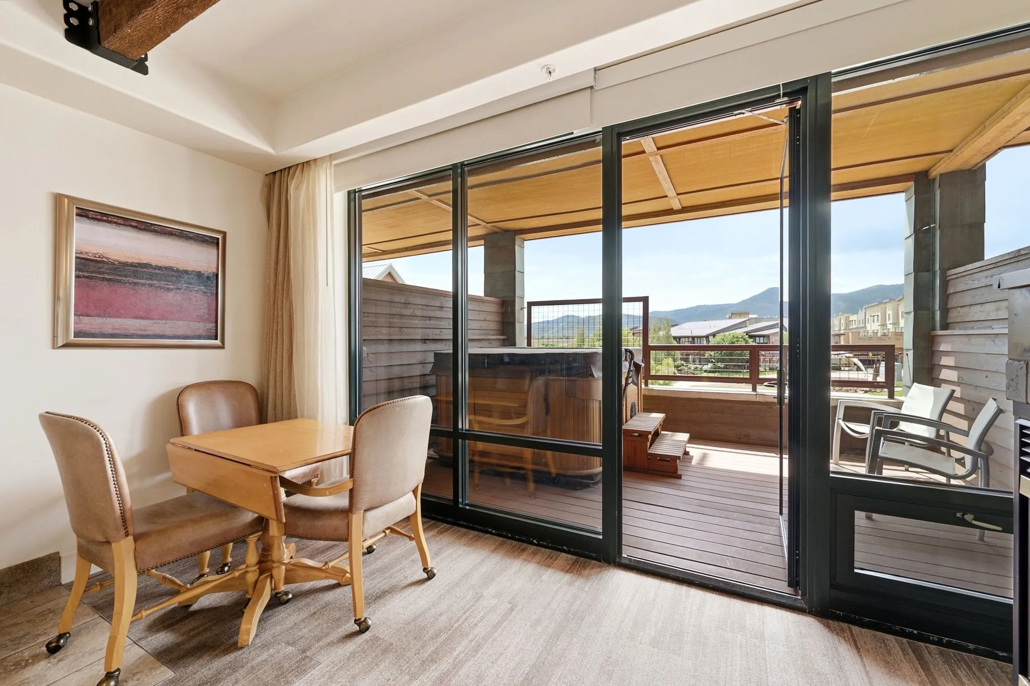 Large sliding glass door, private deck with hot tub, exterior seating, wood-finish flooring, and exposed ceiling beam
