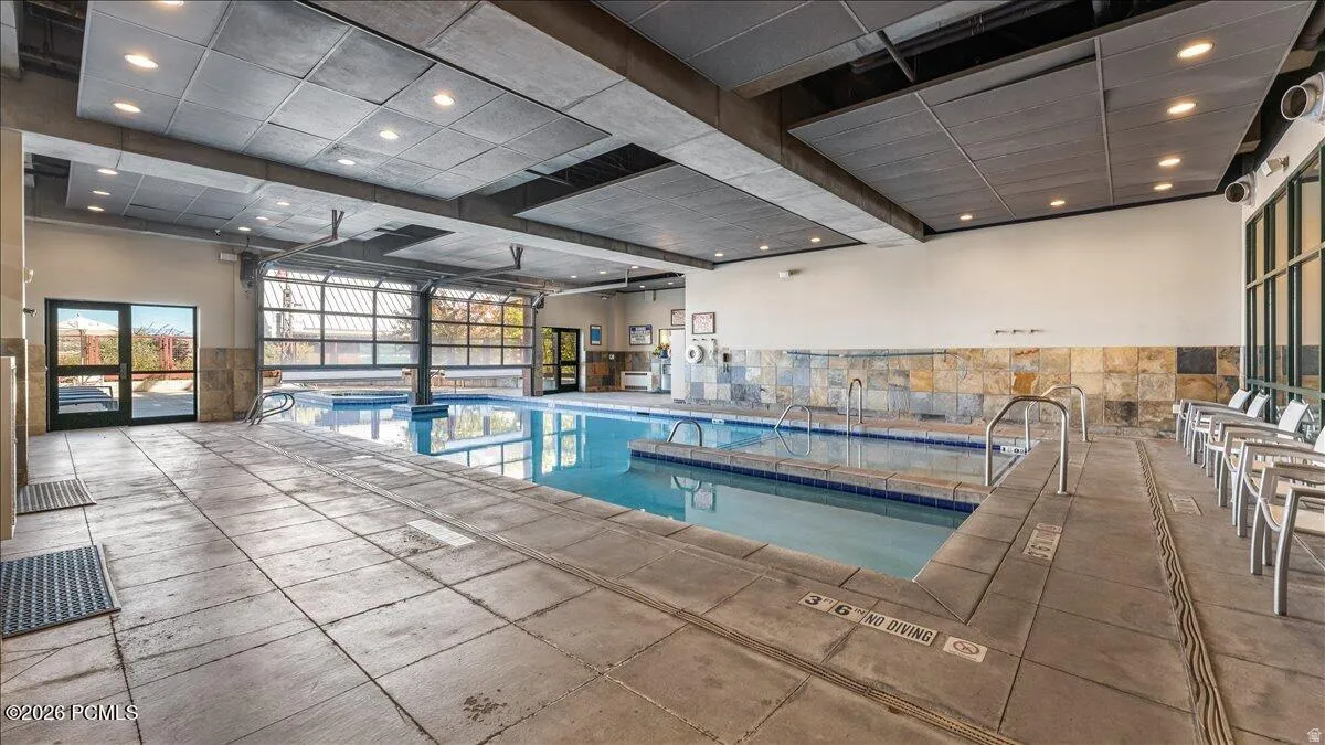 Indoor swimming pool with integrated spa and stone-tiled accent wall