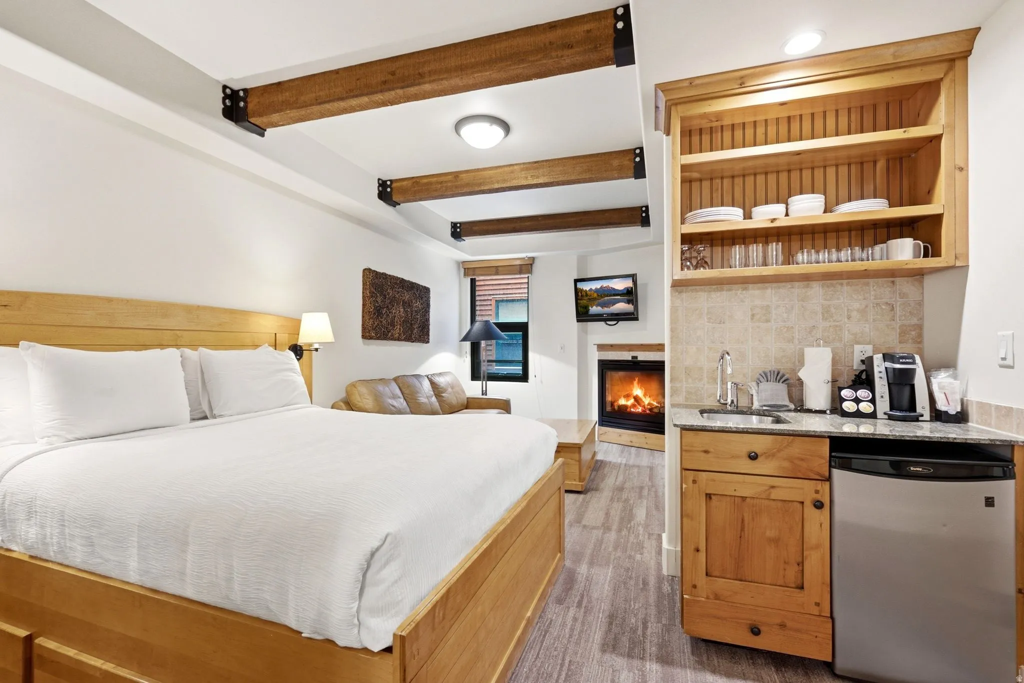 Exposed wood ceiling beams, built-in fireplace, wood-finish flooring, built-in shelving, and granite-finish countertop