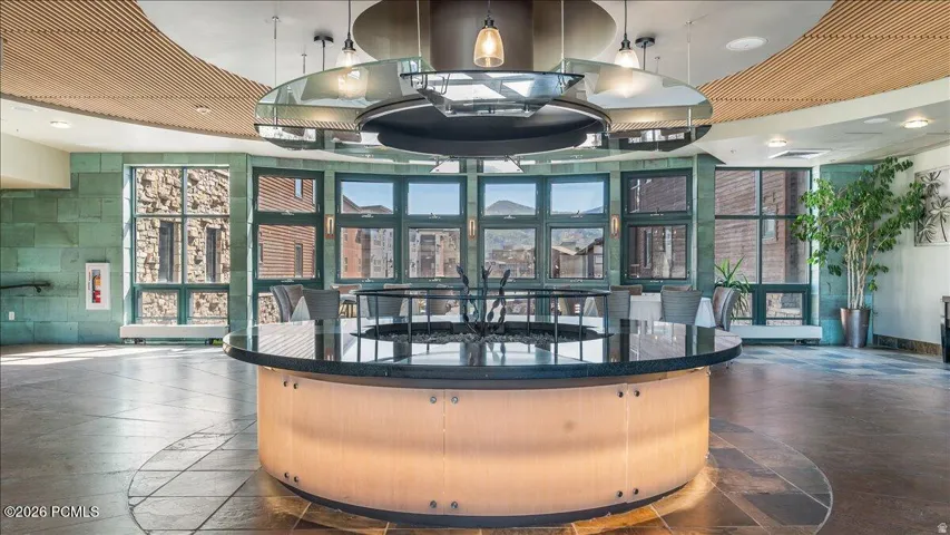 Curved architectural ceiling, stone accent walls, circular central fixture, multiple windows, and tile flooring