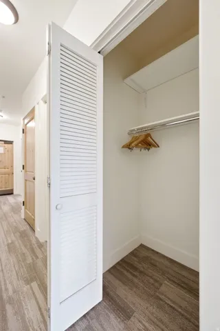 Louvered bi-fold doors opening to a closet with integrated shelving and a chrome hanging rod
