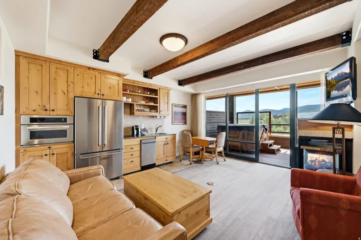 Exposed ceiling beams, full-height glass doors, a built-in fireplace, a built-in microwave, and a stainless steel refrigerator