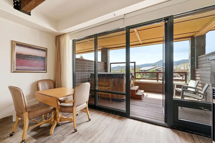 Large sliding glass door, private deck with hot tub, exterior seating, wood-finish flooring, and exposed ceiling beam