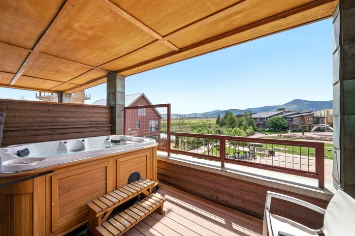 Outdoor hot tub with wood paneling, wood-finish decking, and a slatted privacy wall