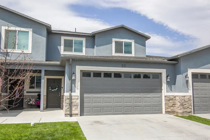 Stucco exterior with stone accents, a two-car garage, concrete driveway, and front door with transom window