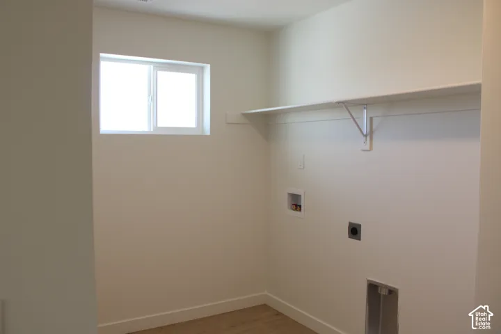 Laundry room featuring a window, built-in shelving, and wood-finish flooring