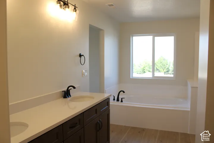 Dual undermount sinks with matte black fixtures, extensive countertop space, integrated soaking tub, and a large window