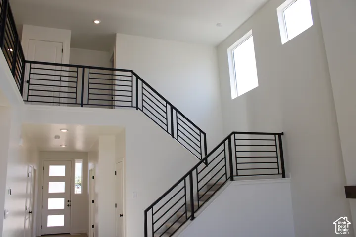 Two-story entryway with high ceilings, modern horizontal bar railings, recessed lighting, and transom windows