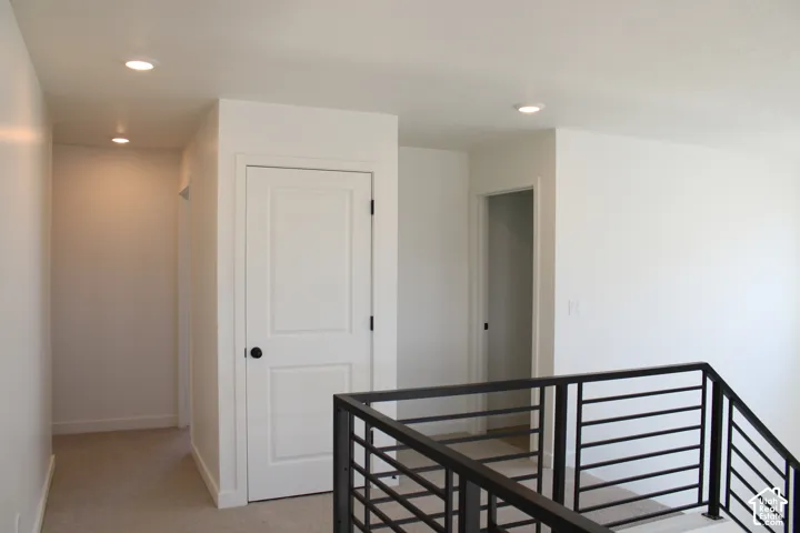 Recessed lighting, white two-panel doors, matte black door hardware, and contemporary metal railing