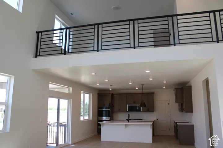 Two-story living area with high ceilings, recessed lighting, a modern horizontal railing, and wood-finish flooring