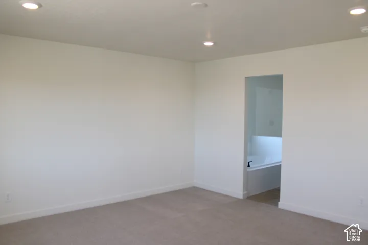 Recessed ceiling lighting, neutral carpeting, and a separate room with a built-in tub