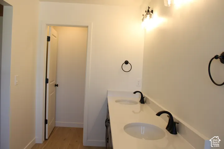 Dual undermount sinks with black bronze faucets, white countertop, and light wood-finish flooring